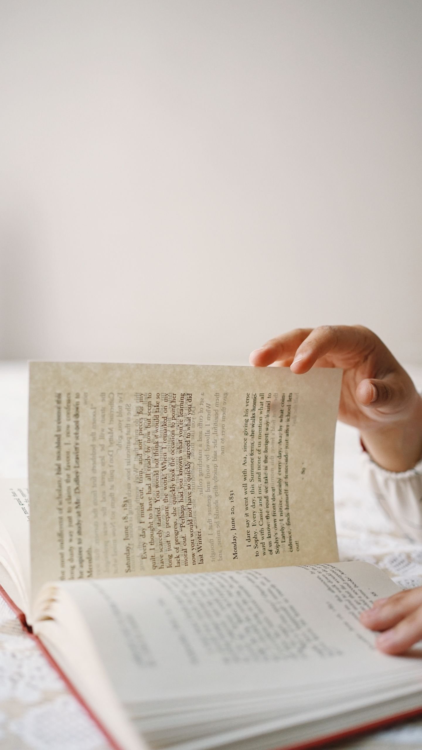 Close-up of a hand delicately turning a book page indoors, emphasizing learning and contemplation.
